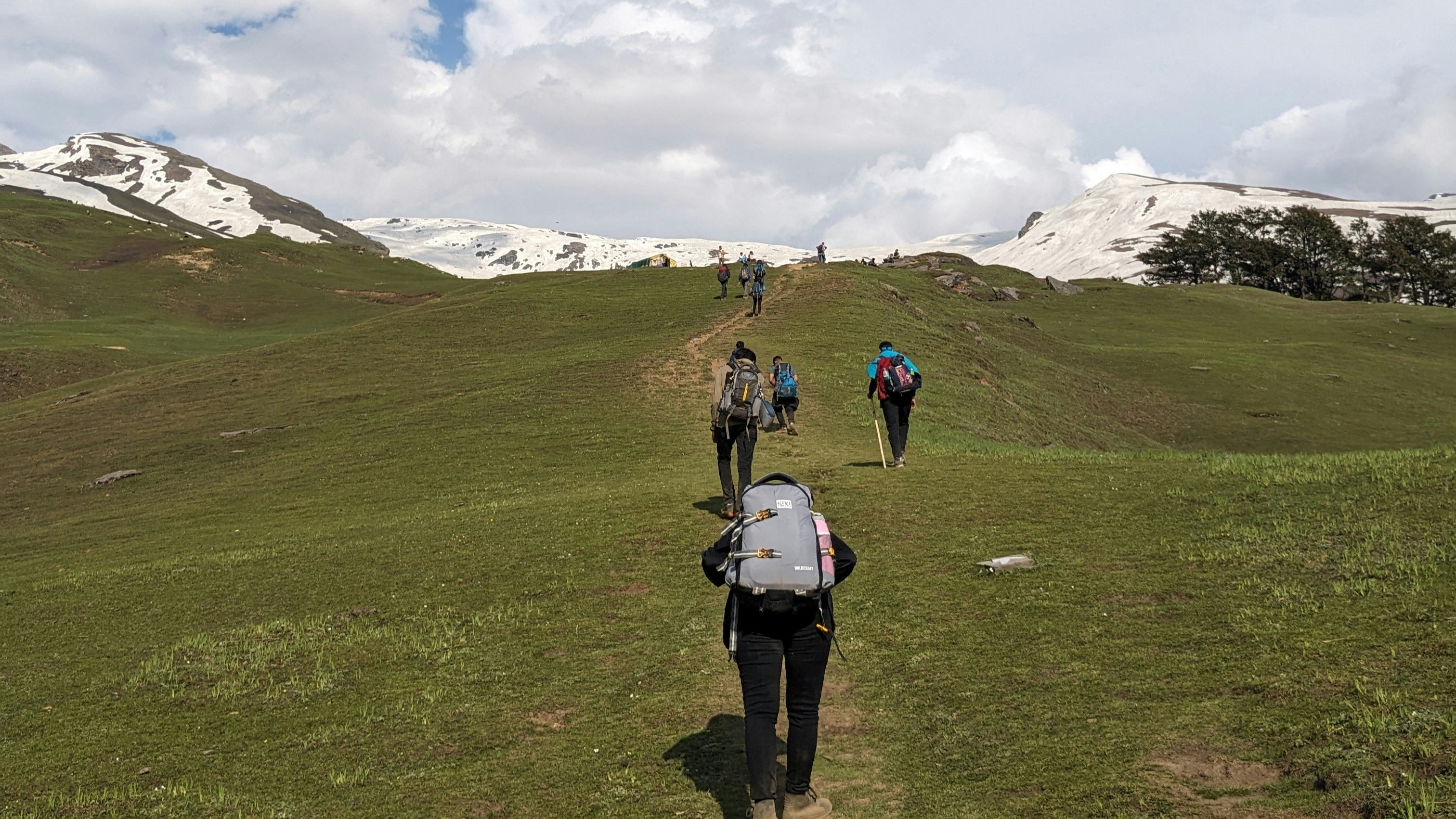 Trekkers walking through the high-altitude meadows of Bhrigu Lake
