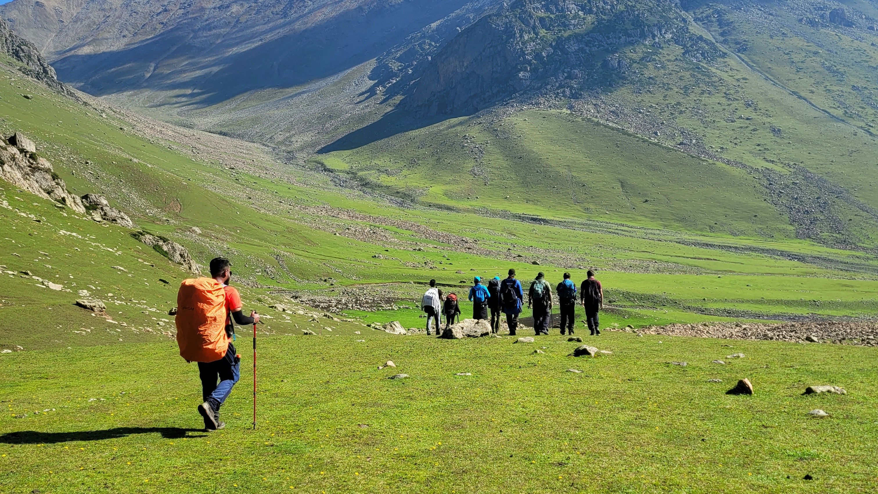 Trekkers crossing the alpine meadows on the Bhrigu Lake trail